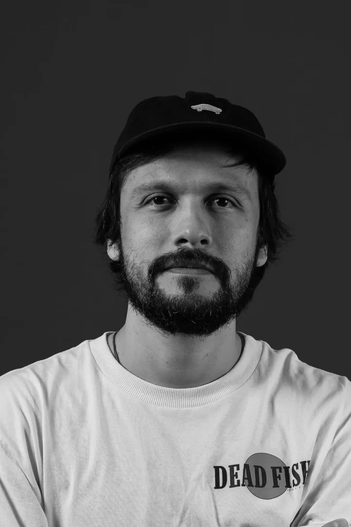 Retrato em preto e branco de Bruno Gabbai, de boné e barba, olhando para a câmera
